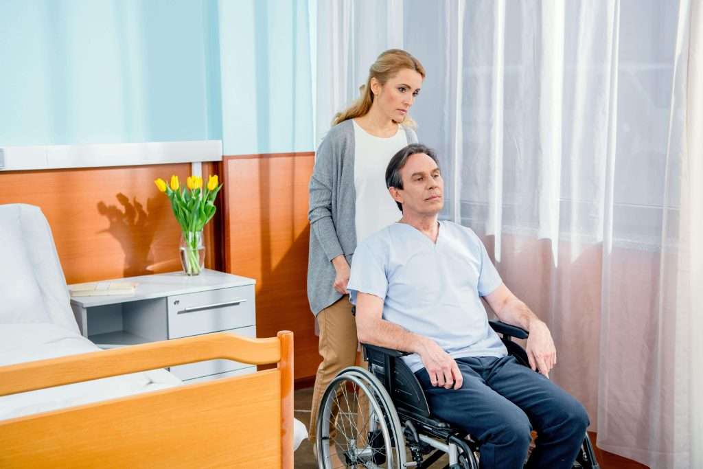 wheelchair-man-with-wife-near-by-in-hospital-chamb-2023-11-27-05-26-48-utc-min